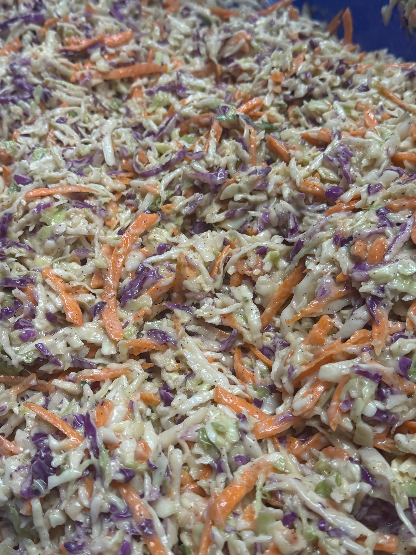 Coleslaw with shredded carrots and purple cabbage on a blue plate